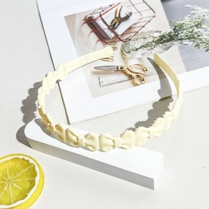 Detail view of cream wavy headband with small bows and non-slip inner teeth structure