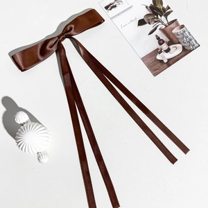Vue macro d'un nœud en satin marron avec de longs rubans fluides pour la coiffure