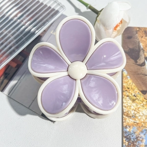 Macro shot of a purple and white plumeria flower hair claw clip with a matte finish