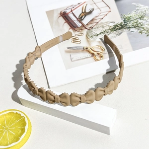 Detail of matte beige bow headband with inner non-slip teeth for secure hairstyling