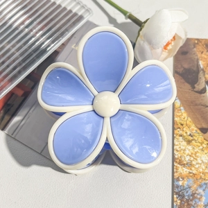 Close-up of blue and white plumeria flower hair claw clip with glossy resin finish