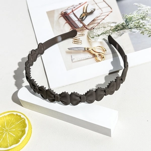 Close-up of matte dark brown wavy headband with non-slip teeth and bow design