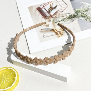 Detail of matte khaki daisy headband showing non-slip teeth and floral resin design