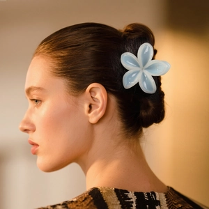 Molla per capelli a fiore azzurro traslucido indossata su uno chignon per un look elegante