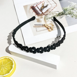 Detail view of black matte wavy headband with floral cutouts and non-slip inner teeth