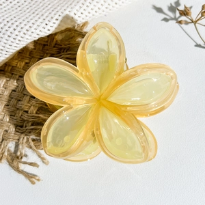 Dettaglio ravvicinato di una molletta per capelli a forma di fiore in resina gialla