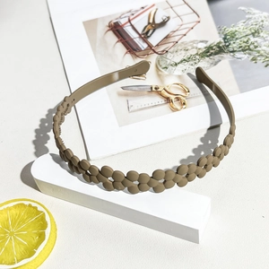 Detail showing matte brown flower chain wavy headband on a minimalist white display