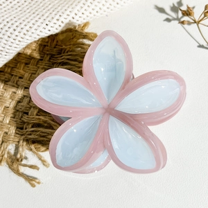 Dettaglio della pinza per capelli a fiore rosa e blu con finitura in resina lucida
