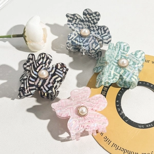 Detail of floral hair claws with pearl center and checkered patterns in multiple colors