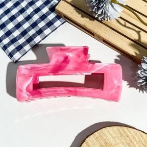 Gros plan d'une grande pince à cheveux rose marbrée avec découpe rectangulaire