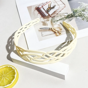 Detail of cream wavy hollowed-out hair hoop on a white geometric display stand