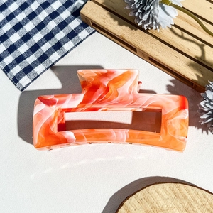 Détail de la pince à cheveux rectangulaire à motif marbre orange et blanc en acétate