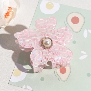 Detailed view of a pink checkered flower hair claw with a central pearl embellishment