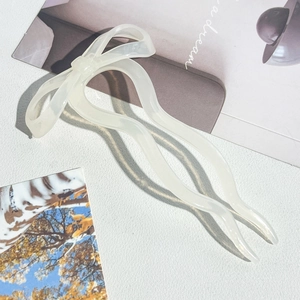 Detailed view of elegant cream-colored bow hair pin with U-shaped acetate design