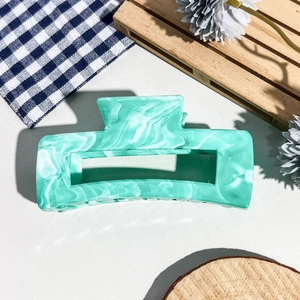 Détail du mécanisme à ressort et de la texture marbrée sur la pince à cheveux menthe