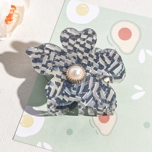 Detail of five-petal flower hair claw clip with grey-blue checkered pattern and pearl