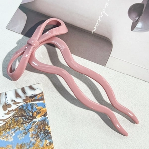 Detailed view of a pink bow hair fork with double-tooth wave design for elegant styling