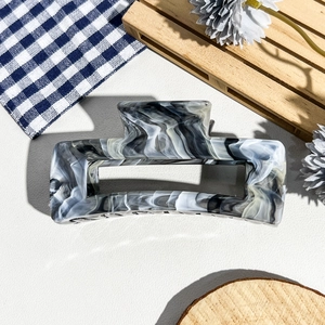 Vue détaillée de la grande pince à cheveux marbrée sur fond décoratif en bois