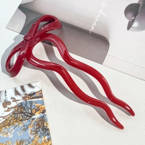 Close-up of a glossy red bow U-shaped hair pin with wave design for elegant hairstyling
