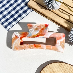 Détail d'une grande pince à cheveux marbrée en acétate orange et bleu avec structure