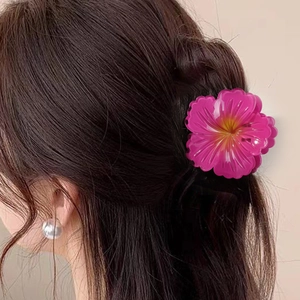 Elegant rose red plumeria flower hair claw clip worn by a model in a stylish hairstyle