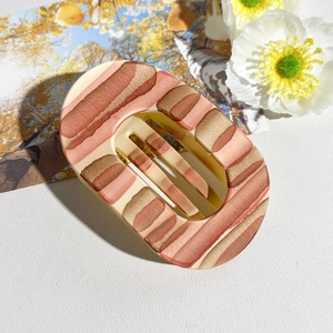 Detail view of oval matte hair claw with creative bacon-like texture and cutout structure
