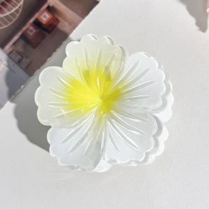 Macro detail of realistic white plumeria flower hair claw clip with gradient yellow center