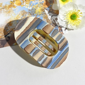 Detail shot of a rectangular tortoiseshell claw clip with blue and brown striped pattern