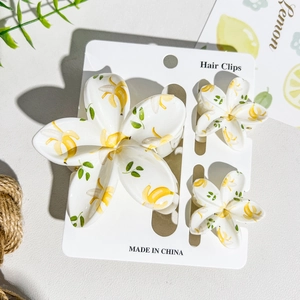 Close-up of three-piece UV printed flower hair claw clips with yellow botanical patterns