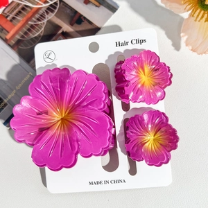 Detail of three purple plumeria hair clips in large and small sizes on card