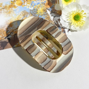 Macro detail of large oval matte hair claw with elegant brown and grey marble pattern