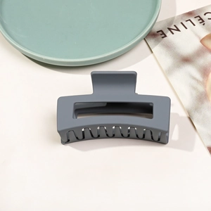 Vue détaillée de la pince à cheveux carrée gris foncé au fini mat sur un magazine de mode