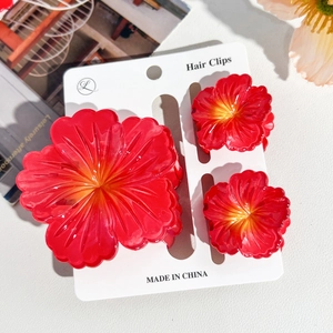Three-piece set of red hibiscus flower hair clips on display card with macro details