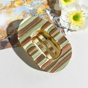 Detail view of oval matte hair claw clip with colorful vintage stripes and inner teeth