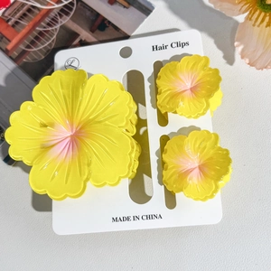 Detailed view of yellow plumeria hair clips in three sizes on a display card
