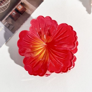 Detailed top view of a red and yellow gradient plumeria hair claw with ribbed petals
