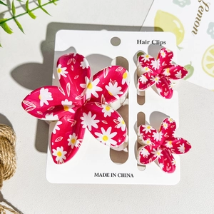 Detail of three-piece red daisy floral print hair clips set on display card