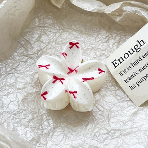 Close-up detail of frangipani hair claw clip with red bow pattern and polished finish