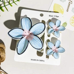 Detailed close-up of light blue floral hair clip set with white hand-drawn petal textures