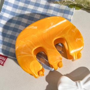 Détail macro de la pince à cheveux en acétate orange marbré avec des dents arrondies antidérapantes