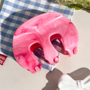 Vue détaillée de la texture marbre rose sur la pince à cheveux courbée en acrylique