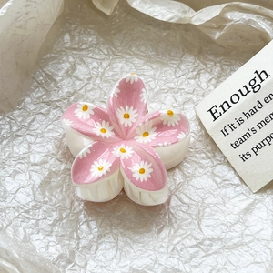 Close-up of pink flower hair claw with daisy prints on a textured white background