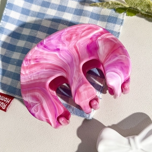 Détail de la pince à cheveux en résine marbrée rose avec une finition brillante et lisse