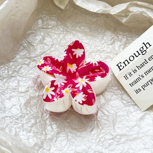 Detailed close-up of a pink frangipani hair claw clip with delicate white daisy patterns