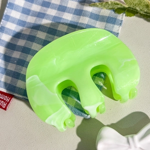 Gros plan d'une pince à cheveux vert clair avec motif marbré sur tissu à carreaux