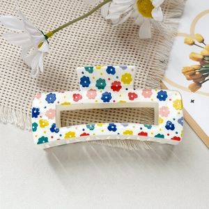 Détail de la pince à cheveux carrée avec motif floral coloré sur cadre en résine blanc