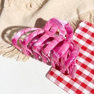 Detail of pink marble acetate hair claw clip with cutout pumpkin design on woven fabric