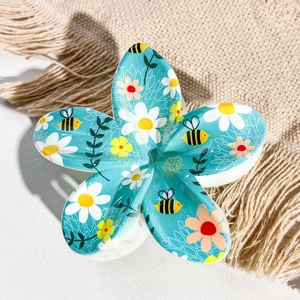 Macro detail of Frangipani hair claw clip with blue UV printed floral and bee patterns