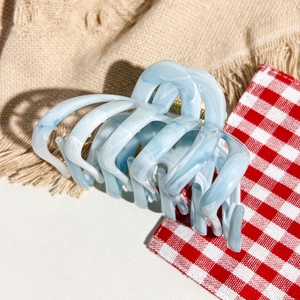 Macro shot of light blue marble acetate claw clip with textured wave pattern