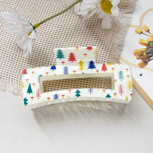Détail d'une pince à cheveux carrée crème avec des motifs de sapins de Noël et de champignons